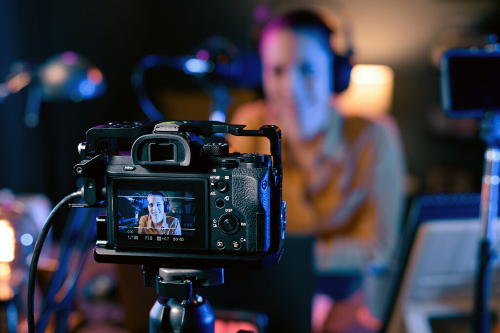 Young youtuber recording a video in her studio, professional camera in the foreground